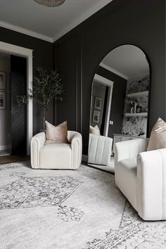 a living room with two white couches and a large rug on the floor in front of a mirror