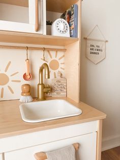 a white sink sitting on top of a wooden counter next to a wall mounted clock