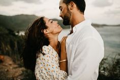 a man and woman standing next to each other near the ocean