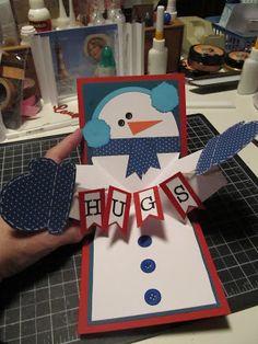 a person holding up a card with a snowman on it, and two other cards in the background