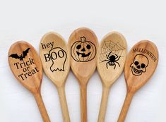 four wooden spoons with carved designs on them, one has a skull and the other has a spider