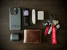 an assortment of personal items laid out on top of a wooden table next to a cell phone