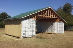 an outhouse made from shipping containers in the middle of a field with a green roof