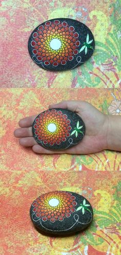 two hand painted rocks sitting on top of a colorful cloth covered surface with flowers and leaves