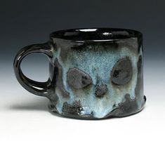 a black and blue coffee cup with skulls on it