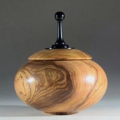 a wooden jar with a black top and handle