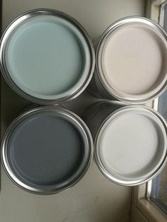 four different colors of paint sitting on top of a window sill next to a door