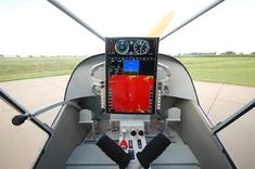 the cockpit of a small airplane with an instrument in it's center and two pilot hands on the steering wheel