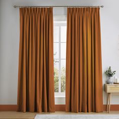 an orange curtain hangs in front of a window with a white rug on the floor