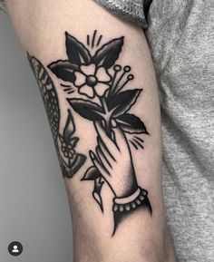 a black and white flower tattoo on the right arm, with an image of a woman's hand holding flowers