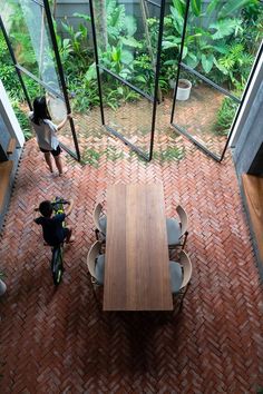 an overhead view of a wooden table and chairs in a room with glass walls that look out onto the jungle