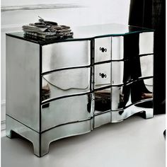 a mirrored dresser sitting in front of a white wall