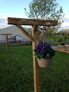 a potted plant hanging from a wooden trellis on top of a grass covered field