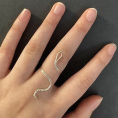 a woman's hand with a silver ring on top of her finger and an open wave design on the band