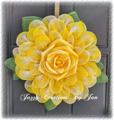 a large yellow flower with green leaves on it's front door hang from the side