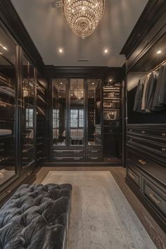 a large walk in closet with black cabinets and chandelier