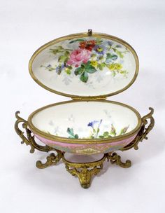 two plates with floral designs on them are sitting in an ornate stand against a white background