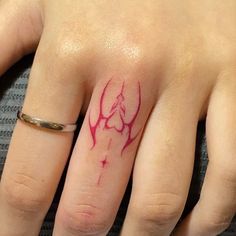 a woman's hand with a red ink tattoo on the middle finger and an arrow in the middle