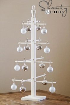 a white christmas tree with ornaments hanging from it's sides on a wooden table