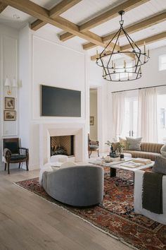 a living room filled with furniture and a fire place under a chandelier hanging from the ceiling