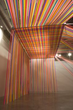 an art installation with multicolored lines hanging from the ceiling