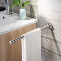 a bathroom sink with a towel rack and flower in a vase