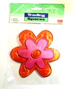 an orange and pink flower shaped applique on top of a white surface next to a packaged package