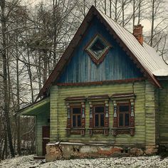 an old wooden house in the woods with snow on the ground