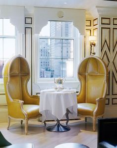 two chairs and a table with a white table cloth on it in front of a window