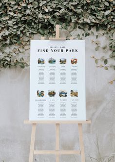 an easel stands in front of a wall covered with greenery and a sign that says find your park