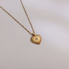 This exquisite gold heart pendant necklace captures the essence of romance and elegance. Featuring a beautifully textured surface and a sparkling central gemstone, it's the perfect piece to express your love and affection. Whether you're dressing up for a special date night or looking for a meaningful gift, this necklace is sure to enchant. Care Instructions   Avoid exposure to harsh chemicals and store them in a cool, dry place. Gently clean with a soft, nonabrasive cloth. Shipping   You Jewelr Gold Plated Heart Pendant Locket Necklace For Valentine's Day, Elegant Gold Plated Locket Necklace For Anniversary, Valentine's Day Gold Plated Heart Pendant Locket Necklace, Valentine's Day Heart Pendant Locket Necklace In Gold Plated, Gold Heart-shaped Birthstone Charm Necklaces, Gold Heart Charm Necklaces With Birthstone, Gold Heart Charm Necklace With Birthstone, Gold Heart-shaped Birthstone Charm Necklace, Gold Plated Heart Pendant Locket Necklace For Anniversary