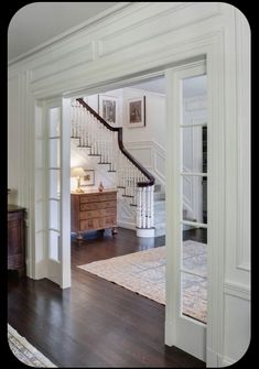 an open door leading to a living room with hardwood flooring and white painted walls