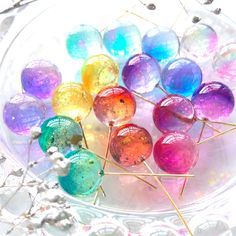 there are many different colored balls in the glass bowl on the table with silver beads