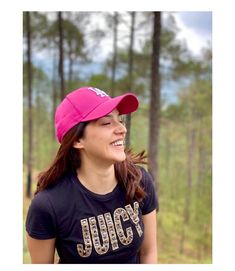 a woman wearing a pink hat standing in the woods