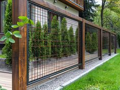 a wooden fence with metal bars on the side of it and trees in the background