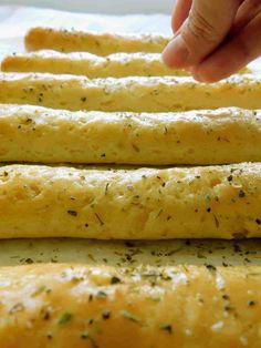 someone is reaching for some bread sticks with herbs on them and sprinkled with seasoning