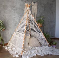 a hammock hanging from the ceiling in a room with potted plants and pillows