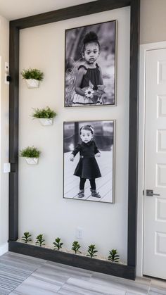 two black and white photos hang on the wall next to a door with potted plants