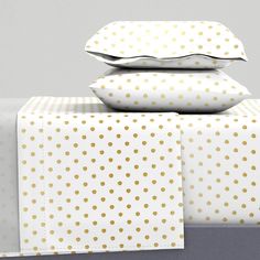 three pillows are stacked on top of each other in front of a bed with pink and white polka dot sheets