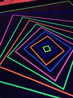 an array of neon colored squares on a black floor in the shape of a square