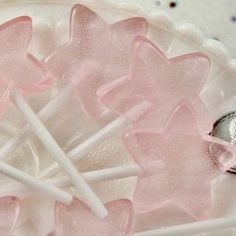 some pink and white lollipops in a bowl with a wedding ring on top