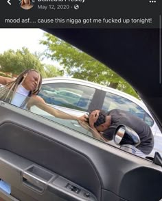 a man and woman leaning out the window of a car, with their hands on the door handle