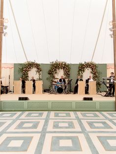 an outdoor stage set up with musical instruments and flowers on the wall in front of it