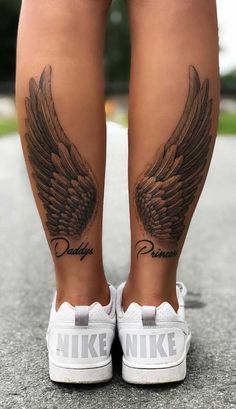 a woman's legs with tattoos and wings on her leg, both showing the word daddy