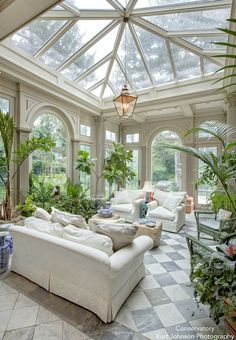 a living room filled with lots of furniture and plants on top of it's walls