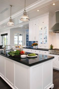 a large kitchen with white cabinets and black counter tops, along with an island in the middle