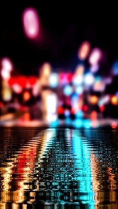 a blurry image of city lights reflected in the wet water at night with reflections on the surface