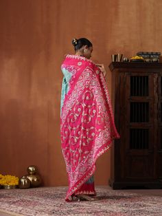 This exquisite saree is a true celebration of India's rich textile heritage, combining three iconic crafts from different regions. The base of the saree is handwoven in Banaras, showcasing the intricate beauty of Banarasi weaving with its luxurious texture and fine craftsmanship. The saree is then adorned with the timeless art of Bandhani, created by skilled artisans in Bhuj, where each dot is carefully tied and dyed to produce vibrant, delicate patterns. To complete this masterpiece, artisans i Traditional Tussar Silk Pre-draped Saree, Semi-stitched Pre-draped Saree With Zari Weaving For Navratri, Festive Semi-stitched Pre-draped Saree For Puja, Festive Handloom Pre-draped Saree For Puja, Festive Katan Silk Pre-draped Saree With Dupatta, Pre-draped Saree With Dupatta For Eid Puja, Traditional Tussar Silk Lehenga With Cutdana, Traditional Art Silk Pre-draped Saree With Zari Work, Tussar Silk Lehenga With Cutdana In Traditional Drape