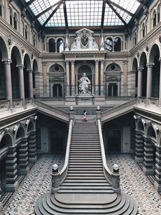 the inside of a large building with stairs and statues on either side of the staircase