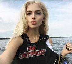 a woman standing on top of a boat in the water with her tongue hanging out